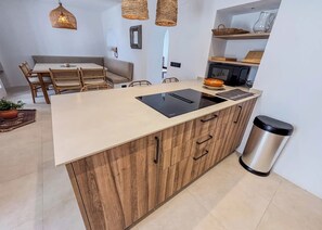 A modern kitchen with a central island, wooden cabinets, a stainless steel sink, and a trash can. - Casa Gina Old Town Marbella Center 4 Bedrooms (Marbella)
