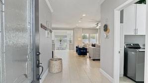 A modern kitchen with a built-in washing machine, a dining area with a table and chairs, and a hallway with a ceiling fan and pendant light. - 3 King Rooms, Sleeps 12 Heated Pool, Waterslide Paradise! 30 Night Min. (Queen Creek)