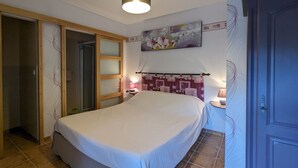 A bedroom with a bed, a door, a wall with a floral painting, and a light fixture. - Countryside Retreat with Spacious Grounds, Pool Access, and Family-Friendly Amenities (Pérassay)