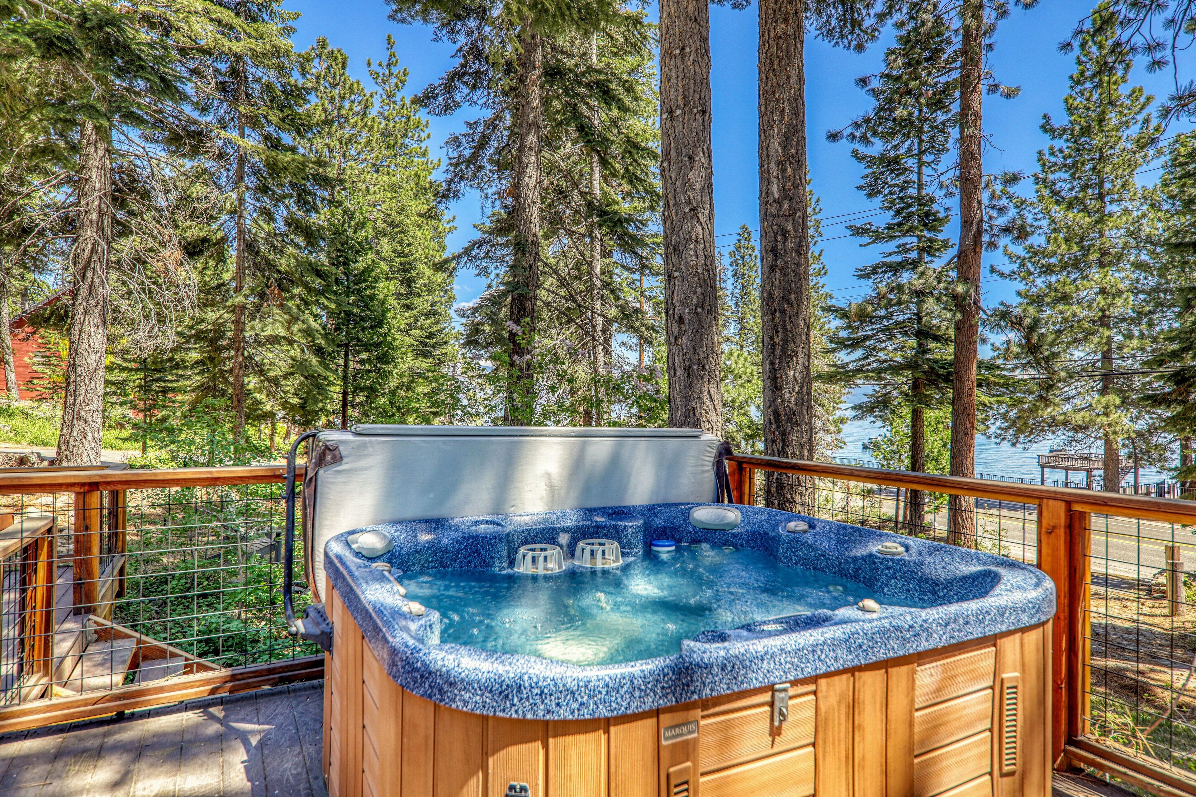 A hot tub surrounded by tall trees and a wooden deck.