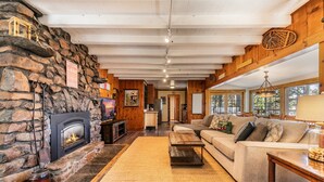 A cozy living room with a stone fireplace, a sofa, and a coffee table. - Reflections Lakeview By Tahoe Getaways - Hot Tub & Buoy, Dog OK (Carnelian Bay)