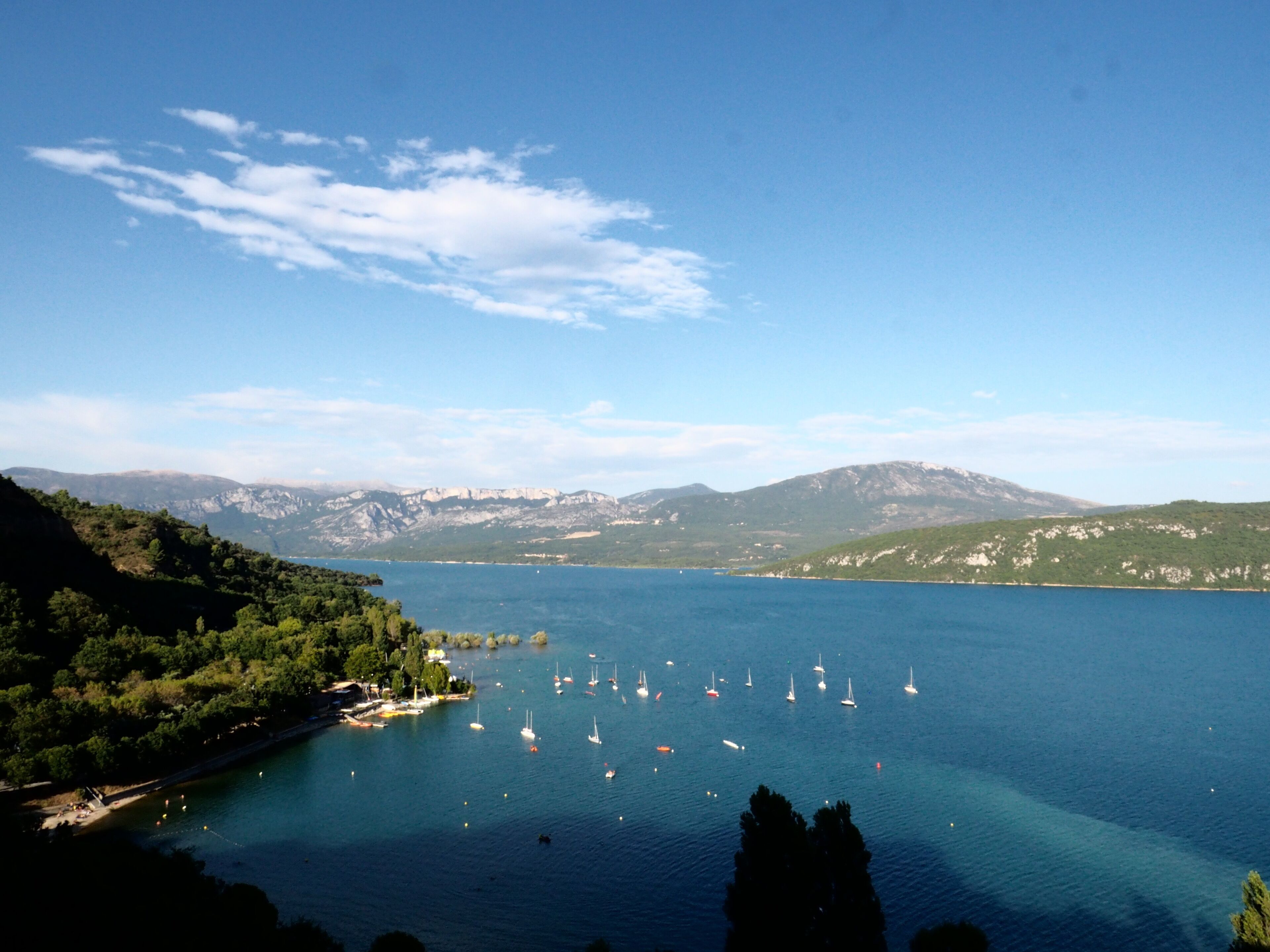 Eine Küstenlandschaft mit freiem Blick auf eine Bucht, Booten und fernen Bergen.
