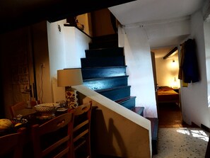 A staircase leading to a bedroom with a bed, a lamp, and a chair with a table.