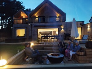 A modern two-story house with a deck, outdoor seating area, and a fire pit. - Villa 15 pers - Spa & Hammam - 5 rooms - La Trinité-sur-Mer (La Trinité-sur-Mer)