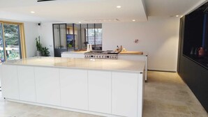 Een moderne keuken met een centraal eiland, witte kasten en een groot raam voor natuurlijk licht.