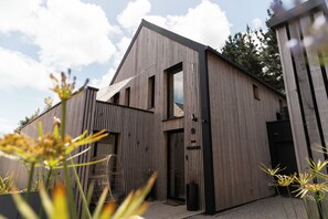 Un bâtiment moderne doté d’une façade en bois, d’une grande fenêtre et d’une porte.