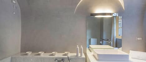 A modern bathroom with a large bathtub, a vanity with a sink, and a mirror.