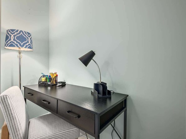 A modern desk with a lamp, a chair, and a pen holder with stationery.