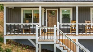 A two-story house with a porch, a front door, and a staircase leading to the upper level.