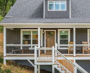 A two-story house with a covered porch, a front door, and a staircase leading to the upper floor.