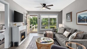 A modern living room with a fireplace, a large sofa, a coffee table, and a television.