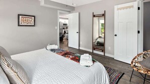 A bedroom with a bed, a ceiling fan, a mirror, and a door leading to another room.