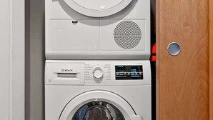 A stacked washer and dryer unit in a laundry room. - 2BR Condo w/ Balcony + Free Tix | Walk to Downtown (Asheville)