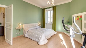 A bedroom with a bed, a standing desk, a treadmill, and a window with curtains. - Lovely 4 bedrooms apartment 30m SanGiovanni metro (Roma)