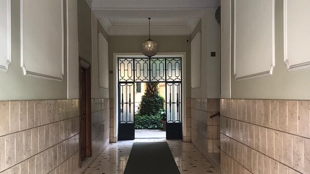 A hallway with a black carpet, tiled floor, and a decorative hanging light fixture. - Lovely 4 bedrooms apartment 30m SanGiovanni metro (Roma)