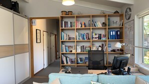 A well-lit room with a large bookshelf, a desk with a computer, and a window with a view.