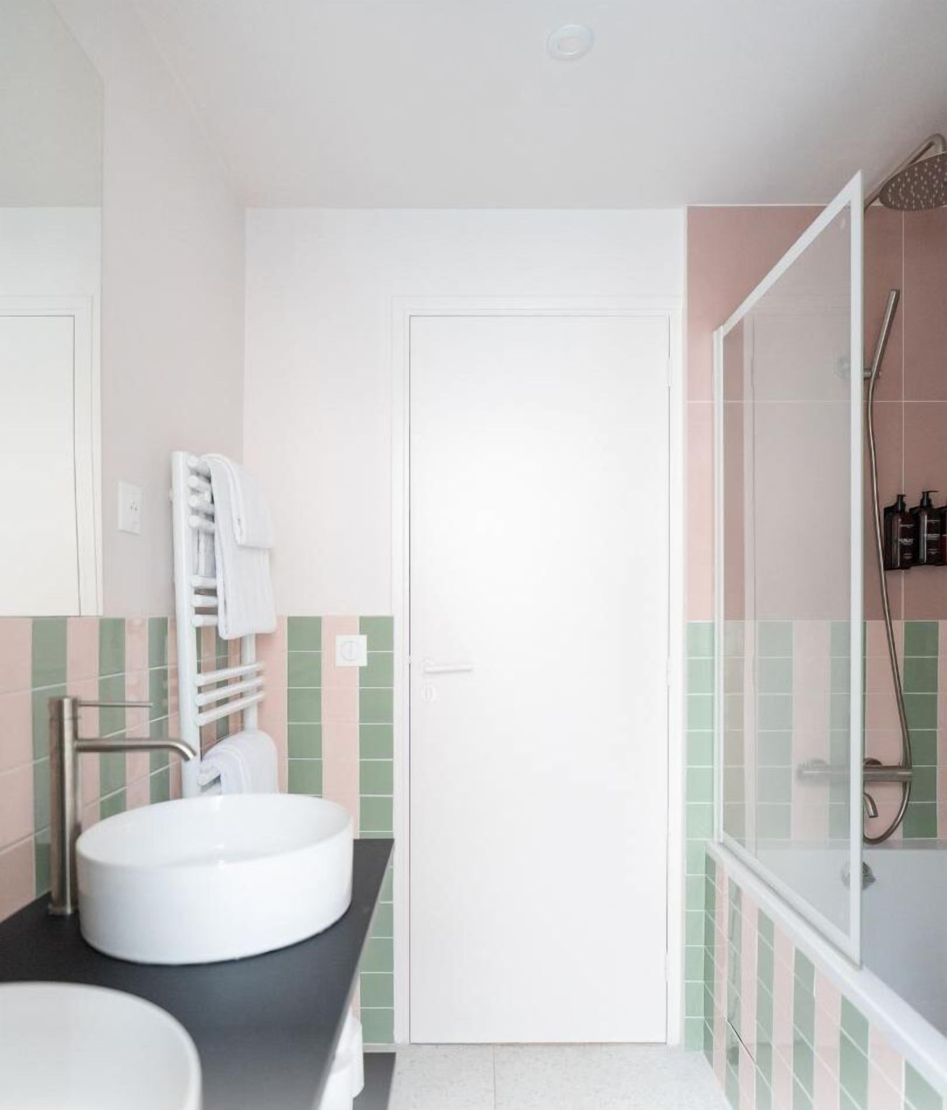 Une salle de bain avec un lavabo blanc, un porte-serviettes et un espace douche.