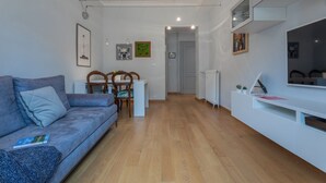 A modern living room with a sofa, dining table, chairs, and a TV unit. - La Casa dei Viaggiatori by Wonderful Italy (Turin)