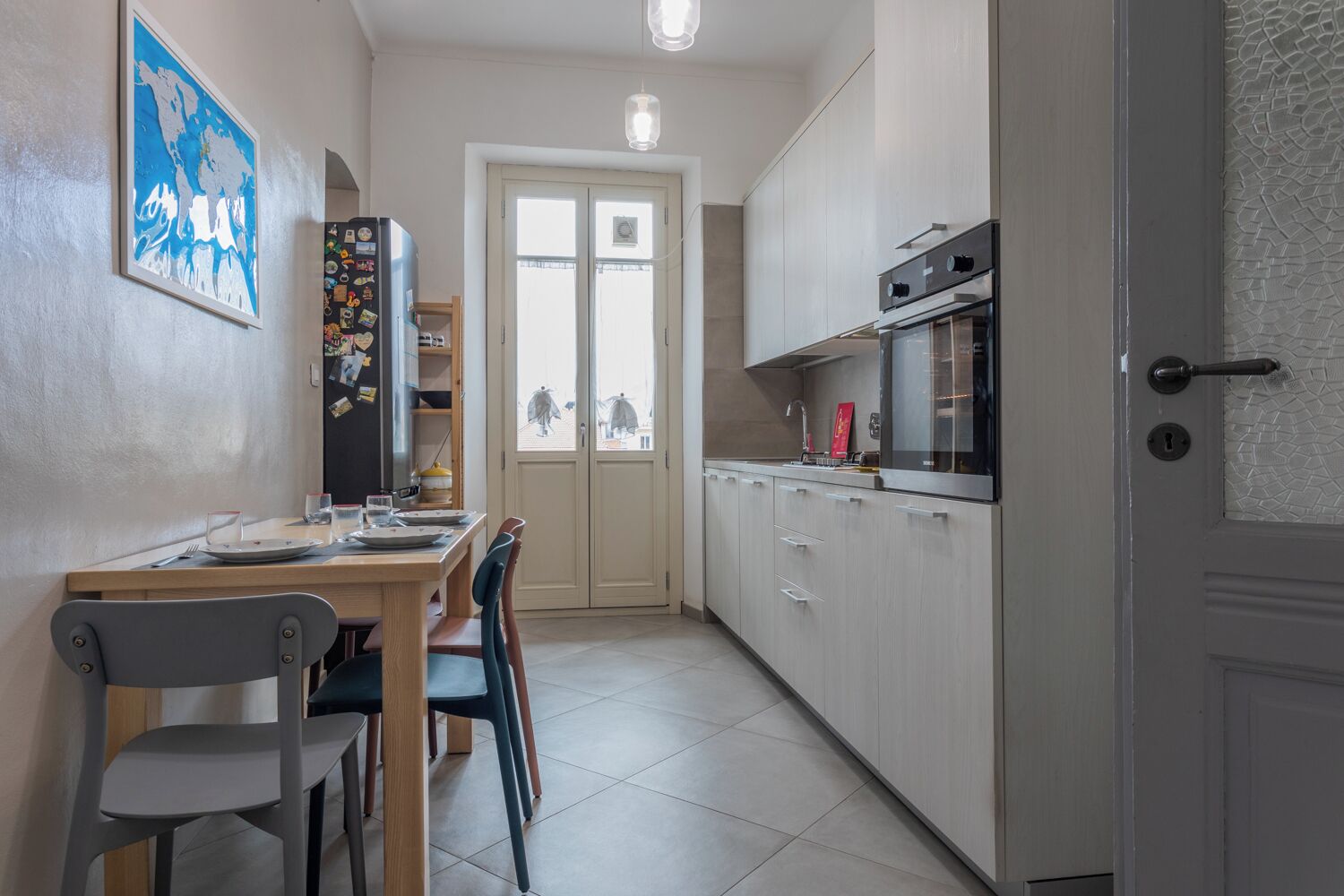 A modern kitchen with a dining area, featuring a refrigerator, oven, and cabinets.