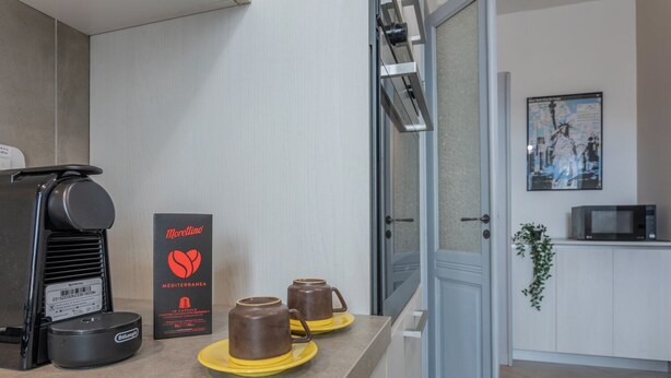 A modern kitchen with a coffee machine, a box of Morellino espresso capsules, and two espresso cups on a yellow tray. - La Casa dei Viaggiatori by Wonderful Italy (Turin)