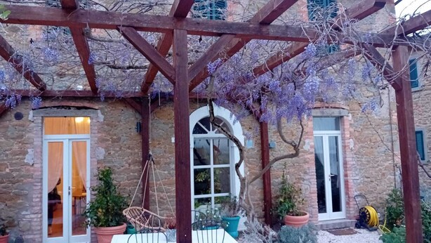 A stone building with a wooden pergola, outdoor seating, and potted plants. - Private Stone Cottage with Starlink & Lake Views - Remote Workers' Dream! (Montecchio)