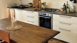 A kitchen with white cabinets, a wooden table, and a stove. - Private Stone Cottage with Starlink & Lake Views - Remote Workers' Dream! (Montecchio)