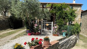 A stone building with a garden entrance, potted plants, and a gravel pathway. - Private Stone Cottage with Starlink & Lake Views - Remote Workers' Dream! (Montecchio)
