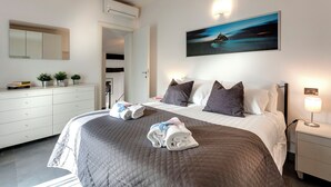 Ett modernt hotellrum med en stor säng, ett nattduksbord med en lampa, en tavla på väggen och en garderob.