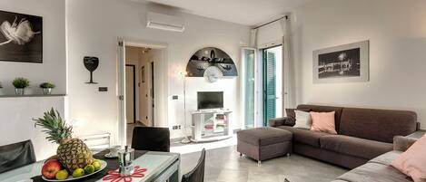 A modern living room with a dining area, a sofa, and a TV.