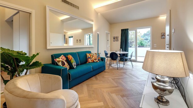 Una sala de estar moderna con un sofá color turquesa, un sillón color beige y un comedor con una mesa y sillas.