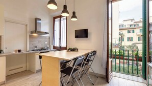 Une cuisine moderne dotée d’un îlot central, de luminaires suspendus et offrant une vue sur la ville depuis un balcon.