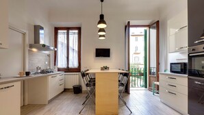 Une cuisine moderne dotée d’un îlot central, d’appareils électroménagers intégrés et d’une grande fenêtre qui laisse entrer la lumière naturelle.