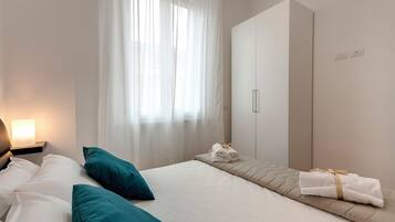 Une chambre d’hôtel avec un lit, une table de chevet, une armoire et une fenêtre avec des rideaux.