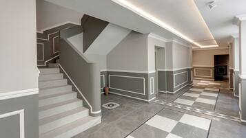 A modern interior with a staircase, checkered floor tiles, and recessed lighting.
