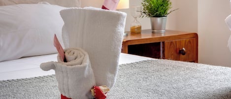 A neatly made towel with a bow, placed on a textured rug in a hotel room.