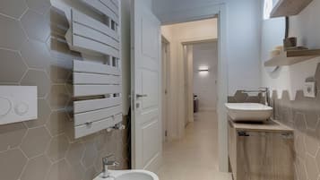 A modern bathroom with a hexagonal tile backsplash, a white sink, and a wooden vanity.