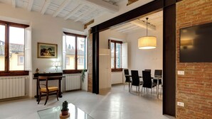 A spacious room with a dining area, a piano, and a large window. - Mamo Florence - Brancacci Apartment (Florence)