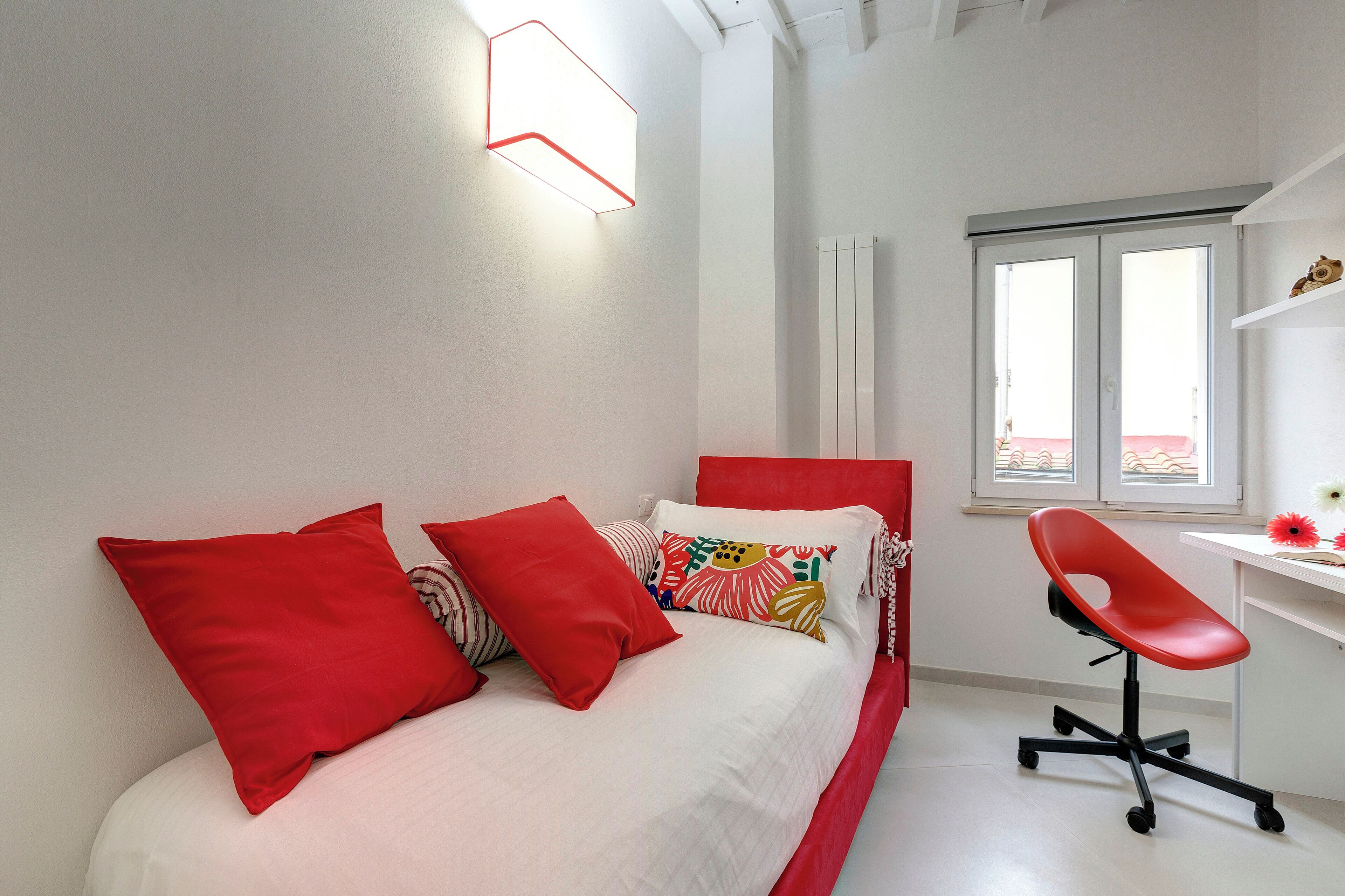 Une chambre à coucher avec un lit, des oreillers rouges, un bureau et une chaise.