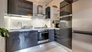 A modern kitchen with a built-in oven, stainless steel appliances, and a marble countertop. - Mamo Florence - Brancacci Apartment (Florence)