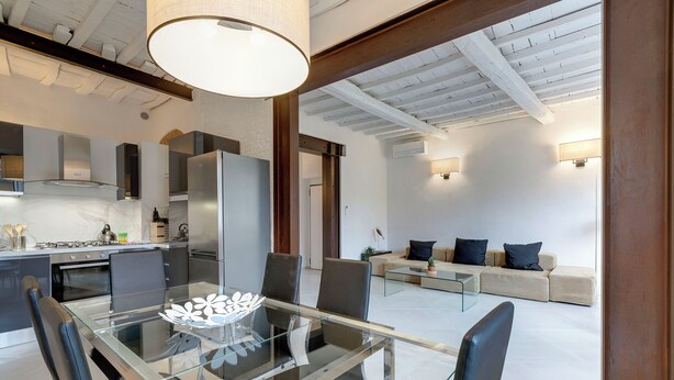 A modern kitchen with a glass dining table, black chairs, and a stainless steel refrigerator. - Mamo Florence - Brancacci Apartment (Florence)