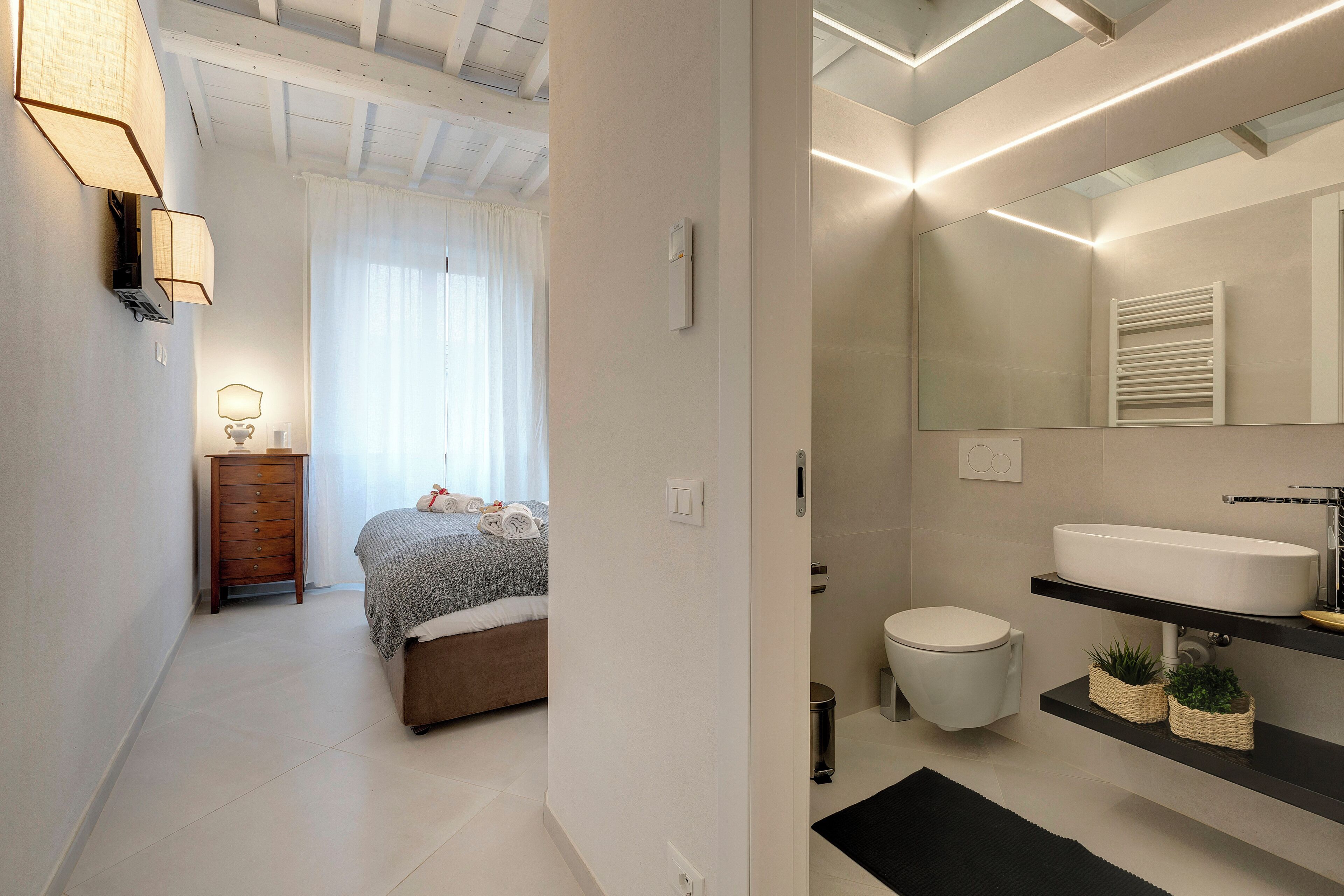 Une salle de bain moderne avec un grand miroir, un lavabo blanc et un plan de toilette noir.