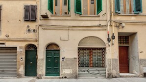 A building with two-story windows, a green door, and a brick entrance. - Mamo Florence - Cloe Apartment (Florence)