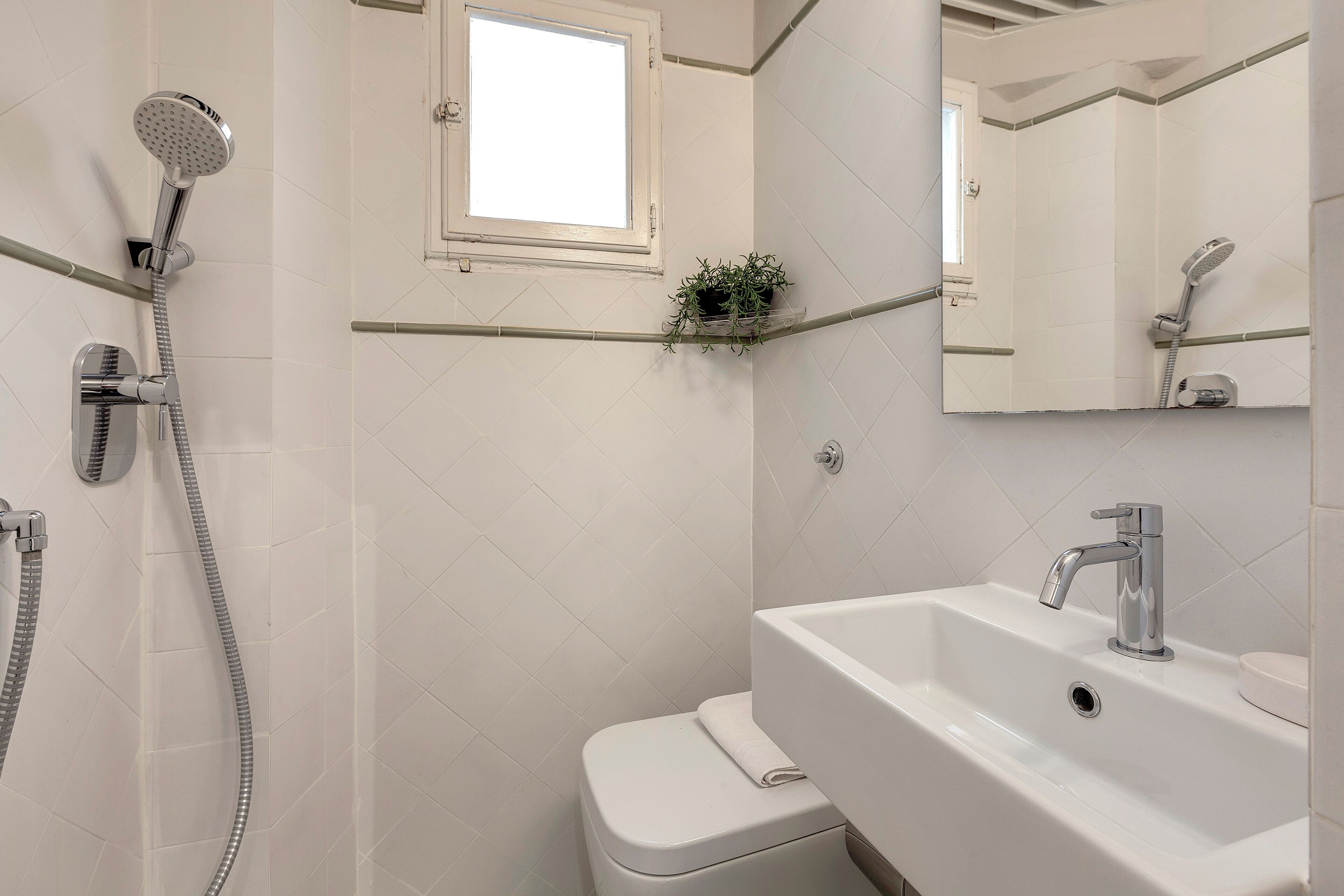 Un baño con ducha, inodoro, lavabo y un pequeño ventanal.