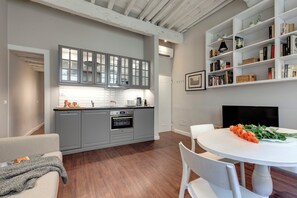 Une cuisine moderne avec des meubles gris, un plan de travail blanc et un coin repas comprenant une table et des chaises blanches.