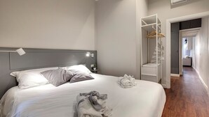 A neatly made bed with pillows, a bedside lamp, and a towel on the floor. - Mamo Florence - Cloe Apartment (Florence)