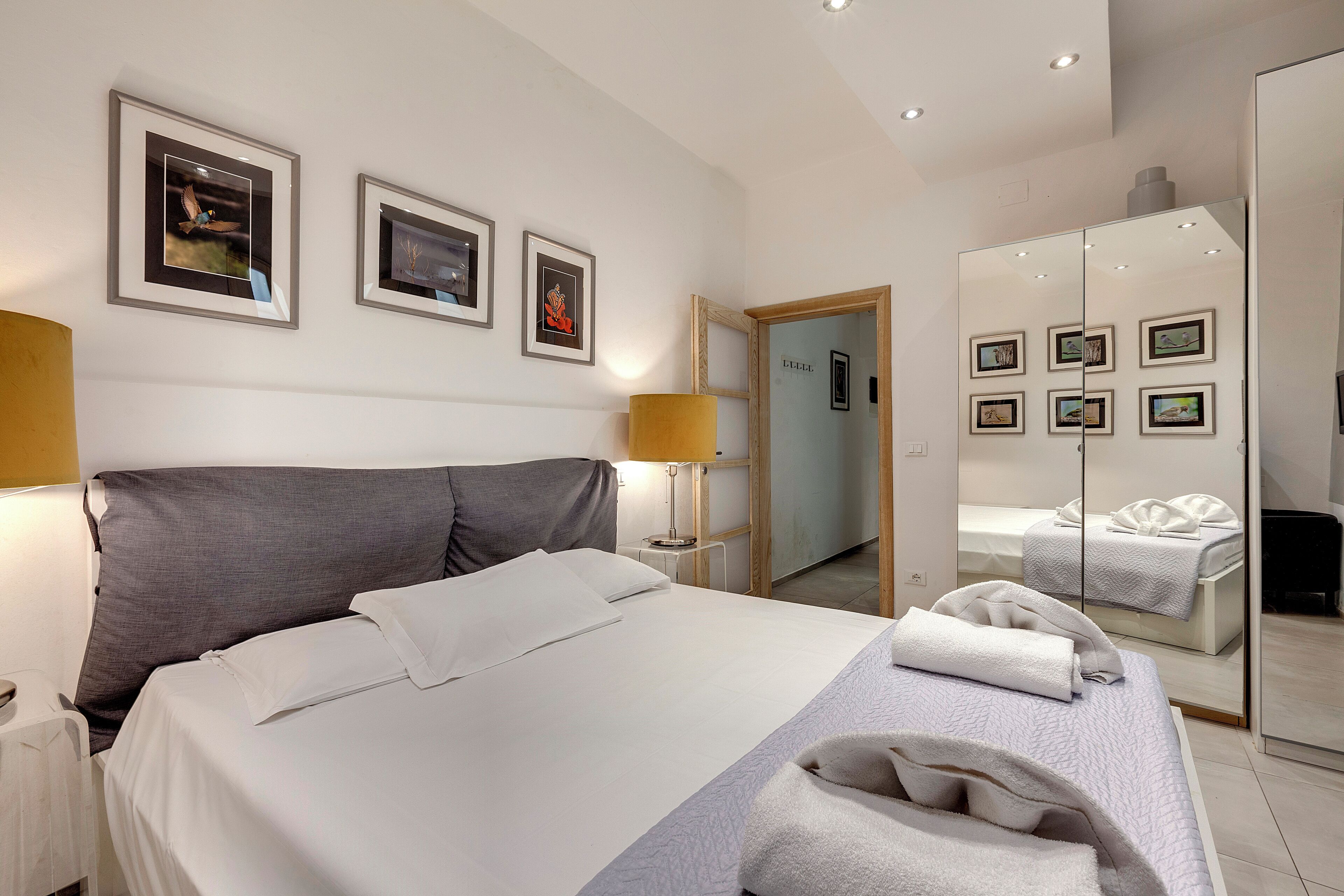 A hotel room with a bed, a nightstand, a lamp, and framed pictures on the wall.