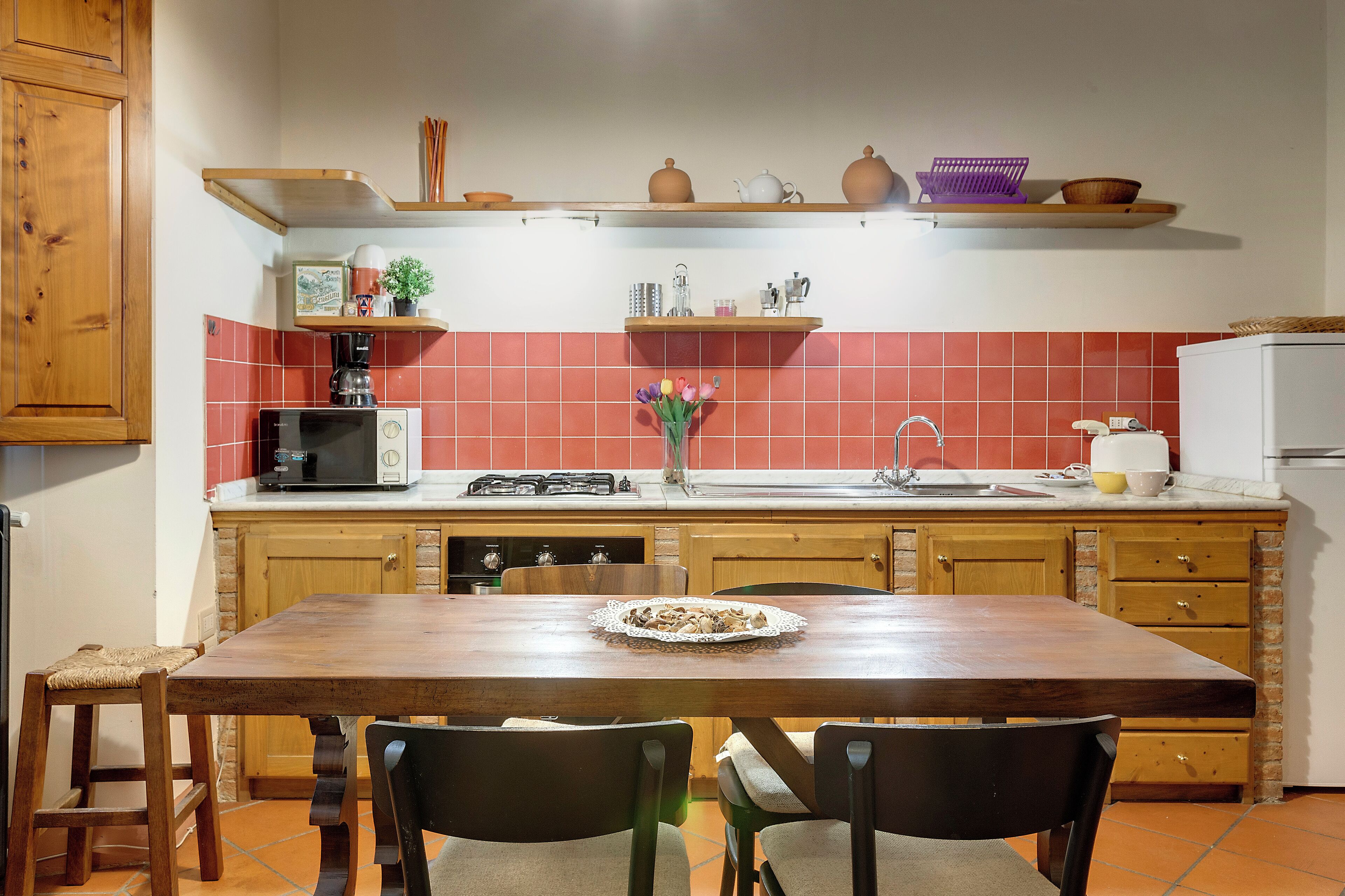 A kitchen with wooden cabinets, a tiled backsplash, and a dining table with chairs.