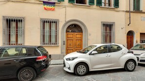 A street scene with parked cars and a building with a wooden door and barred windows. - Mamo Florence - Dafne Apartment (Florence)