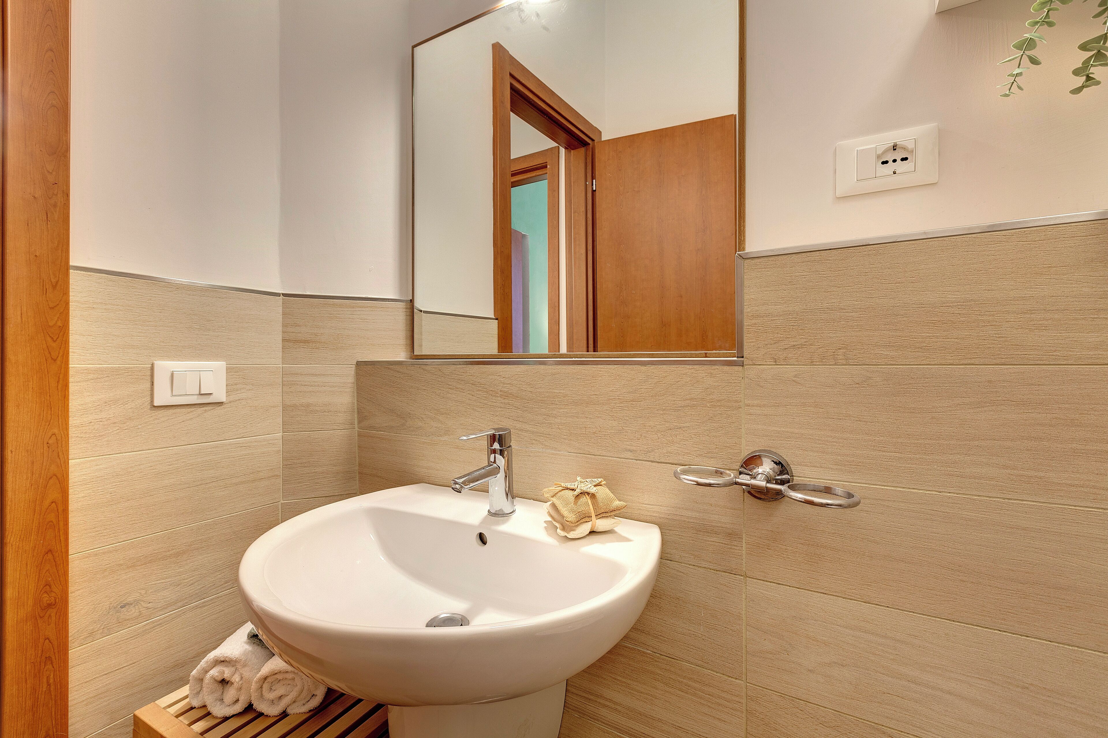 A bathroom with a white sink, wooden paneling, a mirror, and a towel rack.