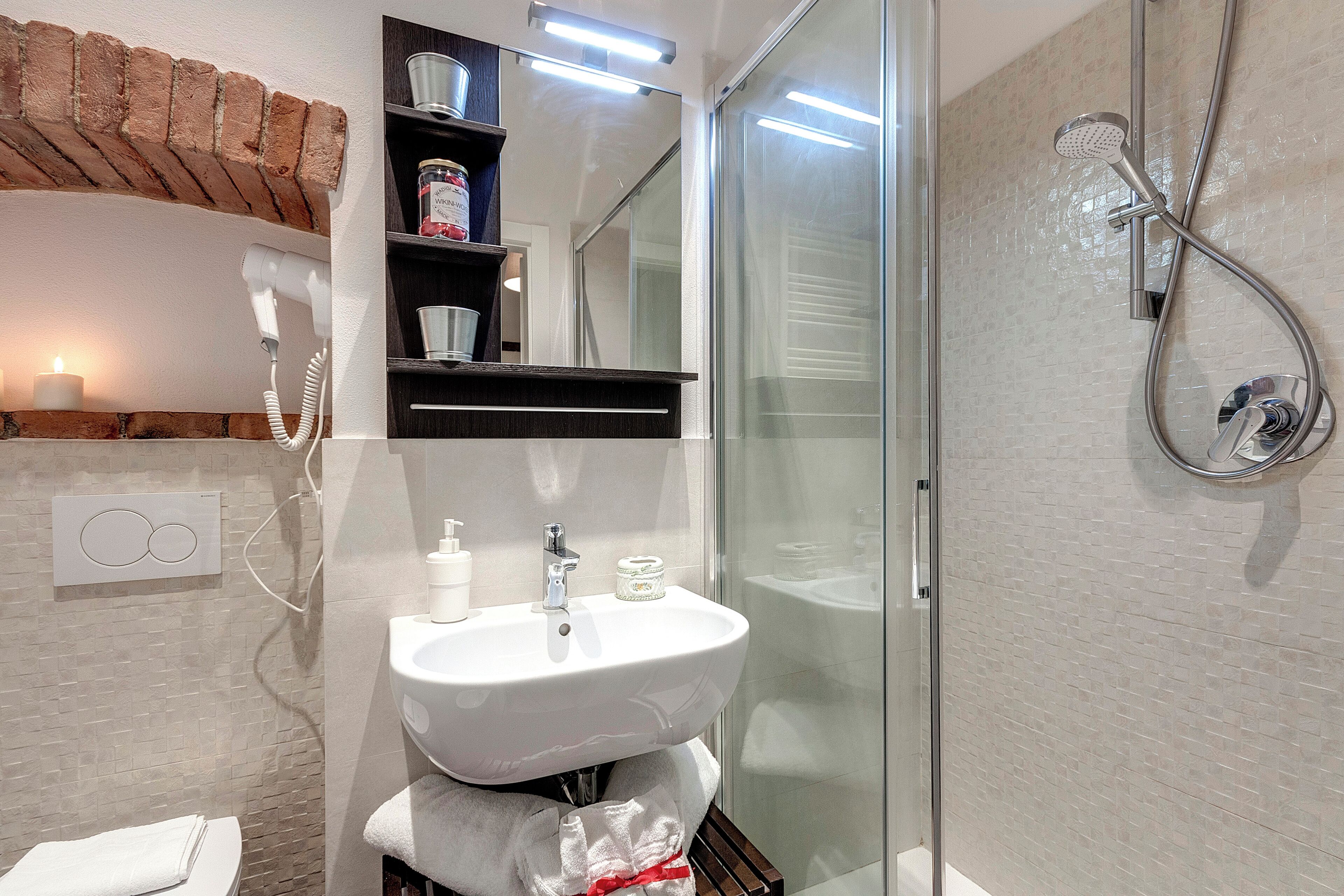 A bathroom with a glass shower enclosure, a white sink, and a towel rack.